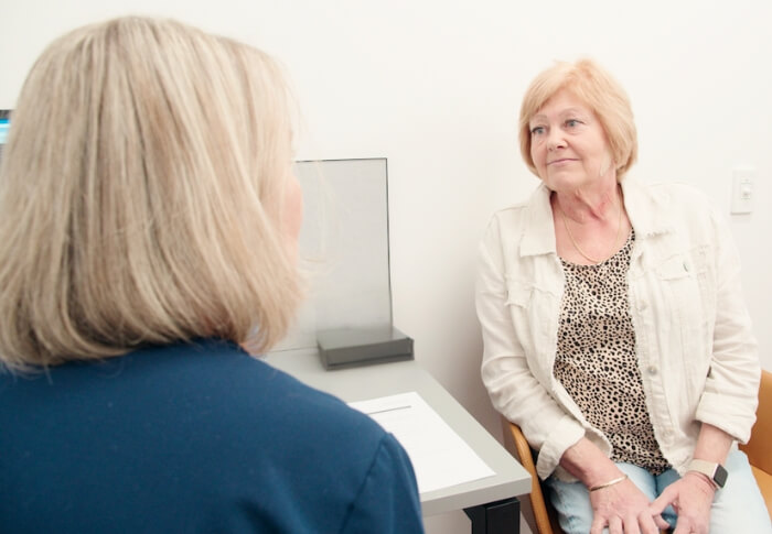 A patient sitting in a consultation room speaking with a healthcare professional.
